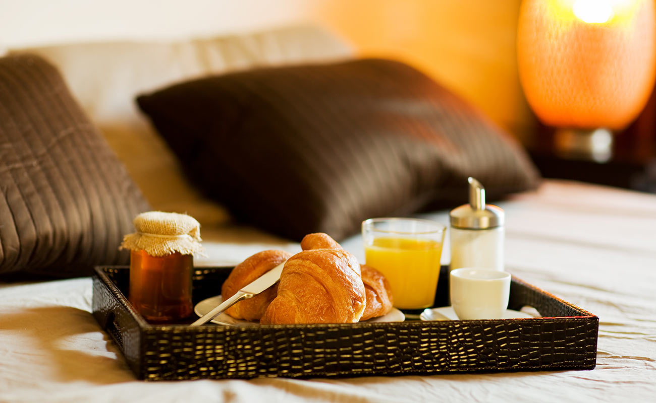 Vassoio con colazione in camera: brioche, miele, caffè e succo d'arancia